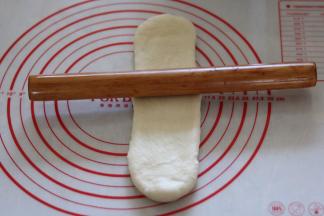 松弛好的面团，继续擀成长舌型，翻面从上往下卷起。