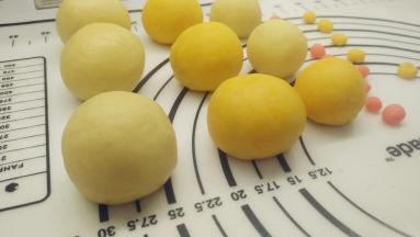 一手大拇指按住馅料，另一手虎口往上推饼皮，使它紧贴着馅料并慢慢地往上爬，最后收口，并将其滚圆。将面团全部包好。