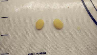 两个1g的黄色小剂子整形成水滴形，做小鸡的两只手，用棉枝蘸一点水，涂抹一下背面，将它们贴在合适的位置。（记得水滴面片的尾端不要完全贴住）。