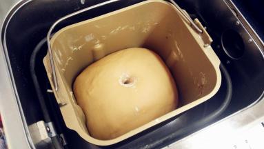 开启面包机发酵程序，一个钟，发酵到面团膨胀两倍大，手指沾面粉戳一个洞，不回缩不塌陷即表示发酵完成。