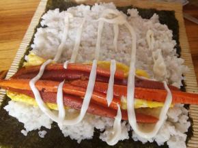 铺上白米饭，前后留一厘米空位，如图，再铺上鸡蛋，胡萝卜，火腿。挤上沙拉