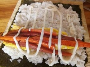 铺上白米饭，前后留一厘米空位，如图，再铺上鸡蛋，胡萝卜，火腿。挤上沙拉