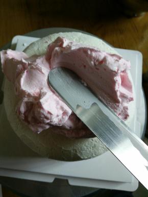 调好开始抹面，搞多点奶油堆到蛋糕上，用抹刀向下边抹边推，左手转动转盘