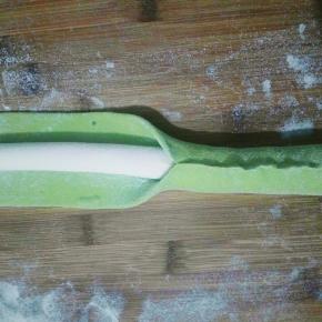 把绿色面条擀开，放进白色包住，然后把绿色捏紧