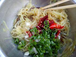 莴笋丝里放入大蒜，葱花，少许盐和鸡精，加入香醋，最后浇上炸好的辣椒，拌匀装盘即可