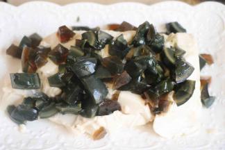 豆腐不用切。直接扣在盘子里就行。然后将皮蛋切成丁，撒在豆腐上