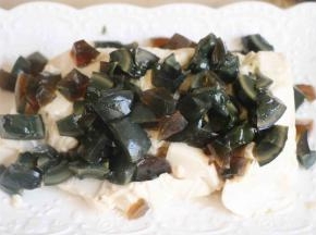 豆腐不用切。直接扣在盘子里就行。然后将皮蛋切成丁，撒在豆腐上