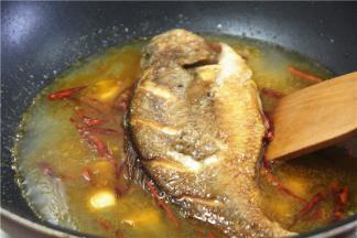 往锅里下50克油，两成温度的时候下姜蒜，辣椒丝炒香，下普宁豆酱40克，再炒一下，倒去适量的水，把煎好的鱼下锅煮开