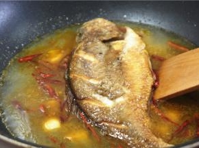 往锅里下50克油，两成温度的时候下姜蒜，辣椒丝炒香，下普宁豆酱40克，再炒一下，倒去适量的水，把煎好的鱼下锅煮开