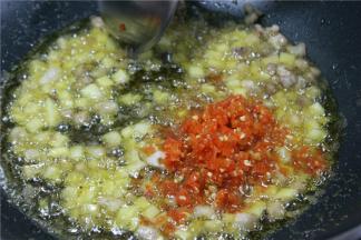 锅中下入少许豆瓣酱、红泡椒碎，混合炒香