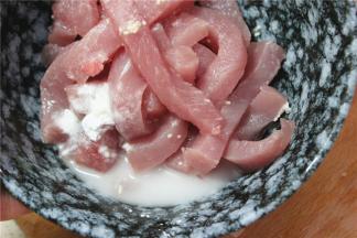 切好的里脊肉放入碗中，加入半勺糖，盐和鸡精，小半勺料酒，加少许的玉米淀粉，抓拌均匀之后腌15分钟入味。