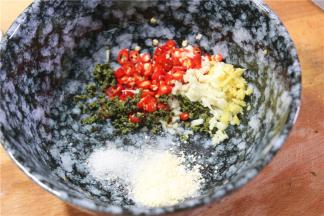 准备一个大一点的碗，放入切好的小米椒，姜蒜末，少许的花椒。然后放入味精，盐。