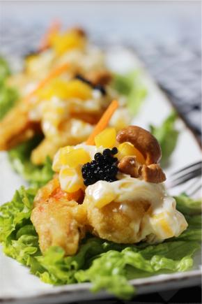 炸好的虾扮上准备好的沙拉酱中，装盘，点缀上腰果和黑鱼籽即可食用