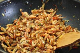 放入炸好的虾，然后调味，加适量的盐，味精和香菜节，快速翻均匀，加一点点香油。