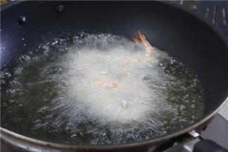 锅内倒入多一点的油，油温七成熟用筷子将虾放下去