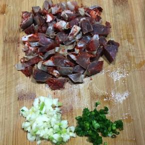 腊肠用开水烫洗一下切丁，蒜头和香葱切碎。