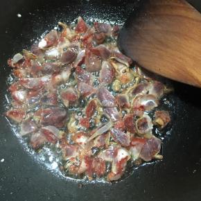 锅中再次加入少许油，中火加热，倒入腊肠翻炒至出油，表面微焦。