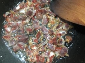 锅中再次加入少许油，中火加热，倒入腊肠翻炒至出油，表面微焦。