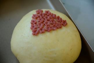 白色面团上刷一层牛奶，把花朵贴在面包上。一朵挨着一朵贴上去，贴成一颗大树状。