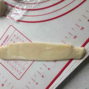 全部面团完成上一步后，继续拿一个面团收口朝上压扁擀成长形，卷起来。