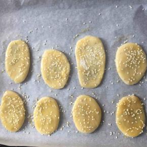 取包好椒盐的面团压扁擀成椭圆形，放入烤盘，涂上全蛋液，撒上芝麻，入烤箱200度烤15分钟