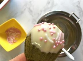 抹茶玛德琳沾上少许白巧克力酱，撒上适量的装饰糖做装饰