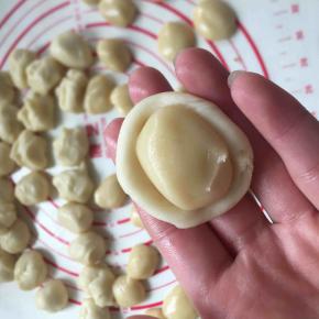 油皮按扁成圆包入油酥，然后收口捏紧朝下放