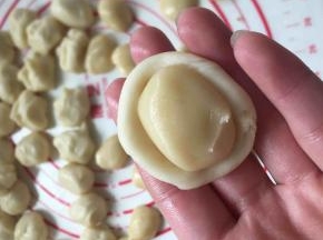 油皮按扁成圆包入油酥，然后收口捏紧朝下放