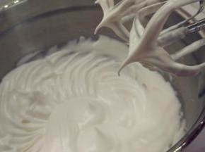往蛋白中分3次加入糖粉，打至中性发泡。（首先，用打蛋器低速将蛋白搅打至起鱼眼泡，加入1/3的糖粉。接着，继续用电动打蛋器高速搅打，至蛋白体积膨胀1倍，再加入1/3的糖粉。然后，继续用电动打蛋器中速搅打，稍微出现纹路，加入剩余的1/3的糖粉。最后低速搅打，直到提起打蛋器时出现小弯钩即可。）
