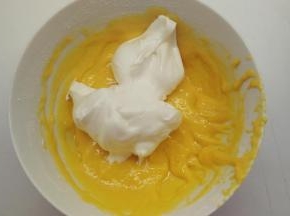 取1/3的蛋白霜加入到蛋黄糊中，用橡皮刮刀用翻拌的手法拌匀。