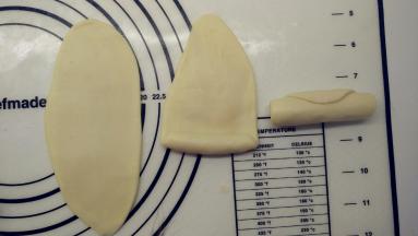 包好的面团收口朝上，用擀面杖擀成椭圆形，由下往上卷一起，这样就完成了第一次擀卷，全部面团都这样操作。