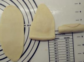 包好的面团收口朝上，用擀面杖擀成椭圆形，由下往上卷一起，这样就完成了第一次擀卷，全部面团都这样操作。