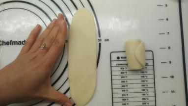 接着来做第二次擀卷，一样将面团收口朝上，用擀面杖擀开，这一次尽量擀成长方形的条状，长度大约等同于张开手指，大拇指和中指之间的距离。