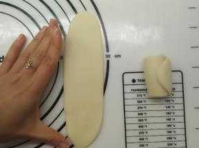 接着来做第二次擀卷，一样将面团收口朝上，用擀面杖擀开，这一次尽量擀成长方形的条状，长度大约等同于张开手指，大拇指和中指之间的距离。