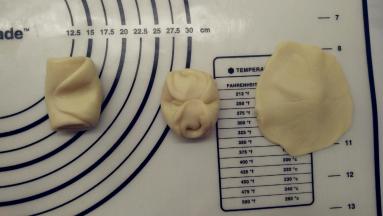 取一份面团，从中间按压下去，将两头按到中间，用擀面杖擀成中间厚四周薄的圆形。