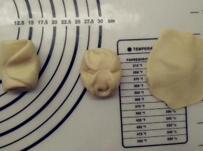 取一份面团，从中间按压下去，将两头按到中间，用擀面杖擀成中间厚四周薄的圆形。
