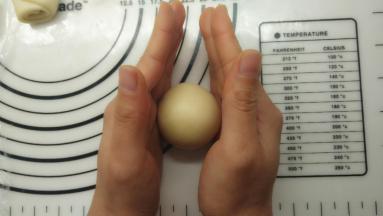 收好口之后将其滚圆。如果还想更圆一些，可以如图所示，两只手平行的滚动面团，很快就可以得到圆滚滚的面团。