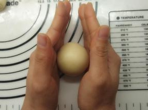 收好口之后将其滚圆。如果还想更圆一些，可以如图所示，两只手平行的滚动面团，很快就可以得到圆滚滚的面团。