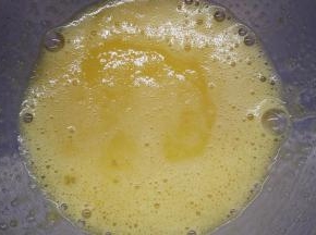 将鸡蛋打散，加入牛奶和柠檬皮屑以及糖粉的混合物，用手动打蛋器将它们搅打均匀。