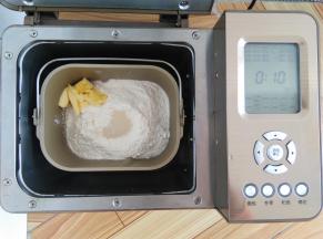 按照先液体再粉末的顺序一次放入主配方中的所有材料，酵母放面粉上，软化好的黄油放一侧角落，启动面包机的和面程序，和面30分钟。这次的配方用的面粉比较多，在和面10分钟后暂停10分钟再继续和面20分钟，有利于保护面包机的电机使用寿命