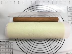 借助擀面杖将蛋糕卷起来，用油纸卷起来放入冰箱冷藏定形30分钟。