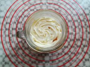 在装芒果泥的杯子里挤上淡奶油