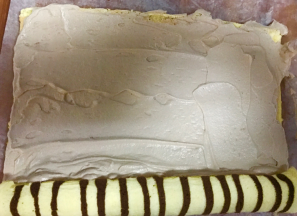 卷好的卷摊开后，抹奶油，尾端少一些，此时已经有定型的效果了，很好卷