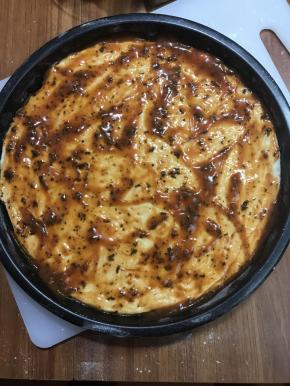 面团擀一下，平铺盘底，用餐叉扎几个孔，涂上披萨酱