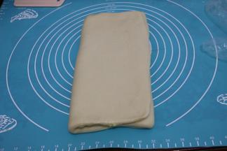 把右边空出的面团折向中间，左边的面团也折向中间，折成一个小的长方形。