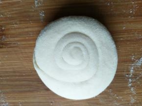 把面片从一头卷起后盘起来，收尾压在下边，擀开成想要的大小