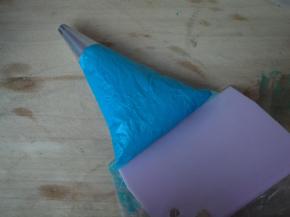 裱花袋装入圆形花嘴，杏仁糊装入裱花袋，用刮板推至花嘴处。