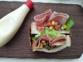 14.	把火腿片卷一下从中间断开，放入切口里，再放些杂蔬，挤上点沙拉酱或者番茄酱都可以，口袋三明治就做好了