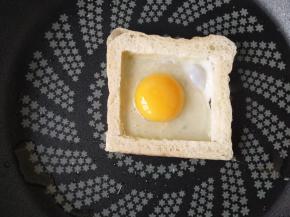 5.	把鸡蛋打入中间的位置，煎熟一面后翻过来煎另一面