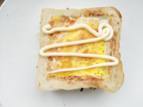 10.	把中间煎有鸡蛋的土司放在生菜丝上，挤上适量沙拉酱